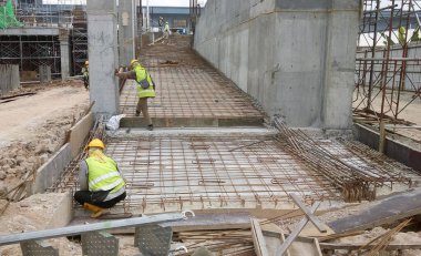 KUALA LUMPUR, MALAYSIA -14 HAZİRAN 2017: İnşaat işçileri inşaat alanında çelik takviye çubuğu üretiyorlar. Destek çubuğu küçük bir kabloyla birbirine bağlanmış..    