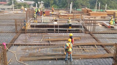 KUALA LUMPUR, MALAYSIA -14 HAZİRAN 2017: İnşaat işçileri inşaat alanında çelik takviye çubuğu üretiyorlar. Destek çubuğu küçük bir kabloyla birbirine bağlanmış..    