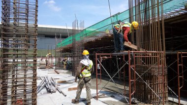 KUALA LUMPUR, MALAYSIA -14 HAZİRAN 2017: İnşaat işçileri inşaat alanında çelik takviye çubuğu üretiyorlar. Destek çubuğu küçük bir kabloyla birbirine bağlanmış..    