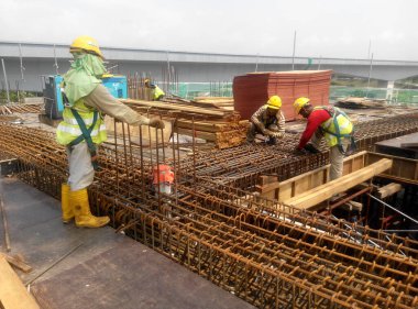 KUALA LUMPUR, MALAYSIA -14 HAZİRAN 2017: İnşaat işçileri inşaat alanında çelik takviye çubuğu üretiyorlar. Destek çubuğu küçük bir kabloyla birbirine bağlanmış..    