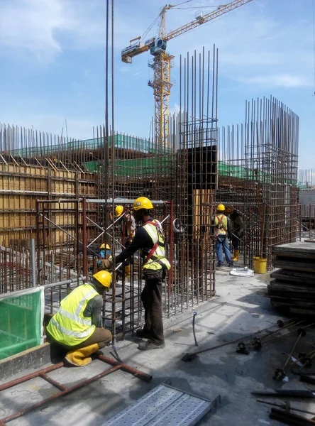 KUALA LUMPUR, MALAYSIA -14 HAZİRAN 2017: İnşaat işçileri inşaat alanında çelik takviye çubuğu üretiyorlar. Destek çubuğu küçük bir kabloyla birbirine bağlanmış..    