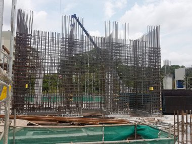 PENANG, MALAYSIA -16 Haziran 2021: İnşaat alanında yapısal çalışmalar devam ediyor. İnşaat işçileri metal ya da kerestelerden yapılmış bir form hazırlıyorlar. Güvenlik özellikleri çok önemli..