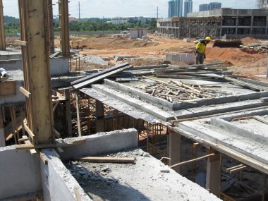 PENANG, MALAYSIA -18 Haziran 2021: İnşaat alanında yapısal çalışmalar devam ediyor. İnşaat işçileri metal ya da kerestelerden yapılmış bir form hazırlıyorlar. Güvenlik özellikleri çok önemli..