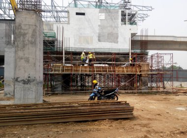 PENANG, MALAYSIA -18 Haziran 2021: İnşaat alanında yapısal çalışmalar devam ediyor. İnşaat işçileri metal ya da kerestelerden yapılmış bir form hazırlıyorlar. Güvenlik özellikleri çok önemli..