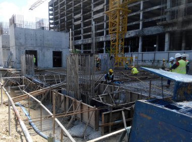 PENANG, MALAYSIA -18 Haziran 2021: İnşaat alanında yapısal çalışmalar devam ediyor. İnşaat işçileri metal ya da kerestelerden yapılmış bir form hazırlıyorlar. Güvenlik özellikleri çok önemli..