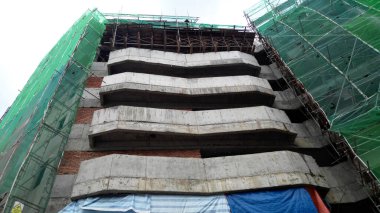 PENANG, MALAYSIA -18 Haziran 2021: İnşaat alanında yapısal çalışmalar devam ediyor. İnşaat işçileri metal ya da kerestelerden yapılmış bir form hazırlıyorlar. Güvenlik özellikleri çok önemli..