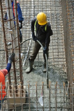 İnşaat İşçileri beton vibratör kullanarak