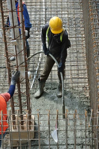 İnşaat İşçileri beton vibratör kullanarak