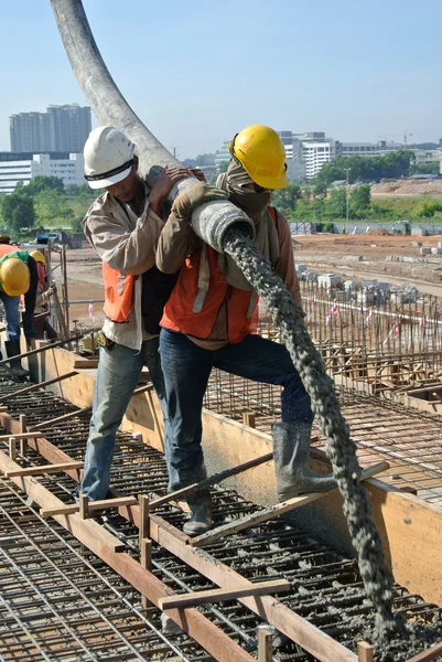 Trabalhadores da construção fundição de concreto usando mangueira de concreto — Fotografia de Stock