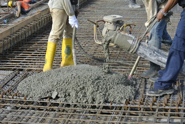 Stavební dělníci lití betonu pomocí betonové hadice Stock Snímky