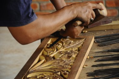 Skilled craftsman doing wood carving using traditional method clipart