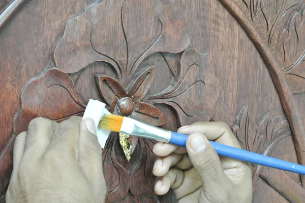 Skilled craftsman adding gold leaf skin to the wood carving — Stock Photo, Image