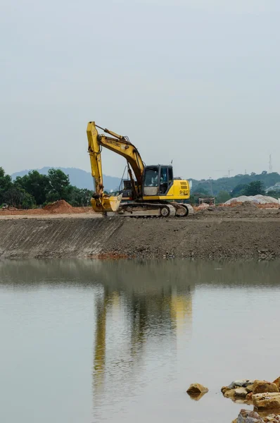 A máquina escavadora fazendo terraplenagem ao lado do lago — Fotografia de Stock