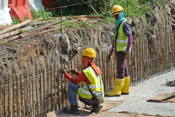 Construction workers fabricate retaining wall reinforcement bar at the construction site.