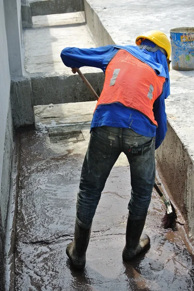 A construction worker apply layer of waterproofing at the building roof slab surface