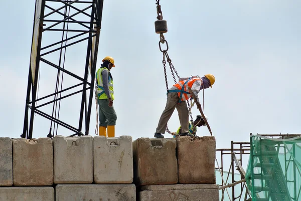 Trabajadores de la construcción levantando bloque de prueba de carga en el sitio de construcción — Foto de Stock