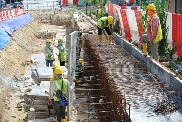 Trabajadores de la construcción fabrican barras de refuerzo de muro de contención y encofrados en el sitio de construcción . — Foto de Stock