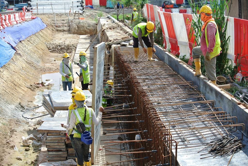 Construction workers fabricate retaining wall reinforcement bar and formwork at the construction