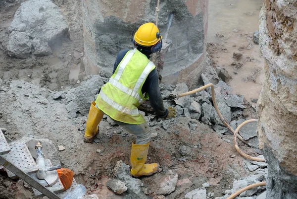 Construction workers using mobile concrete hacker at the construction site