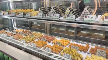KLIA2, Malaysia -October 26, 2025: Various types of sushi are displayed on a retail shelf behind a clear glass window. Customers can view and select the fresh food, which is priced and protected for hygiene and quality.