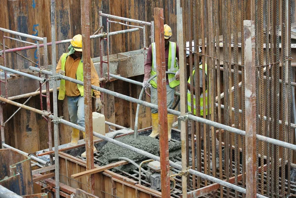 Stavební dělníci pomocí betonové vibrátor na kompaktní beton — Stock fotografie