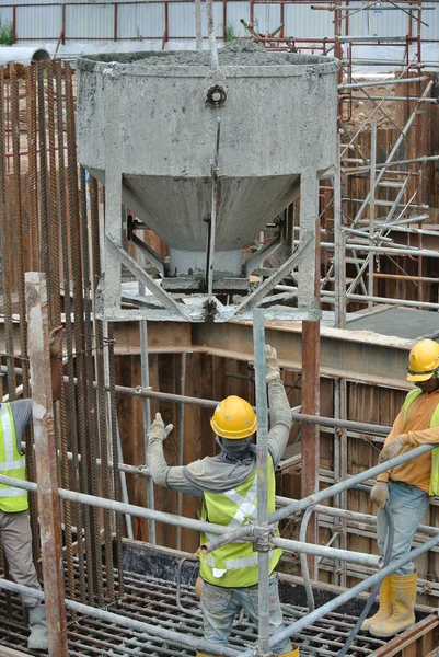 Eine Gruppe von Bauarbeitern gießt Beton in eine Pfahlschalung — Stockfoto
