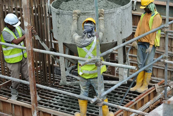 Um grupo de trabalhadores da construção que despeja concreto na cofragem do bloco — Fotografia de Stock