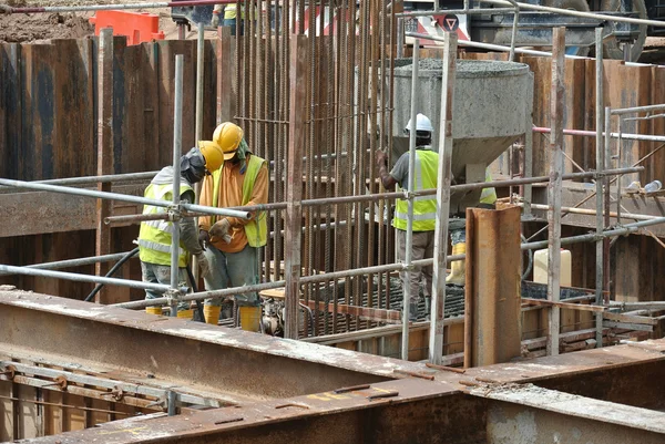 Travailleurs de la construction utilisant un vibromasseur en béton pour compacter le béton — Photo