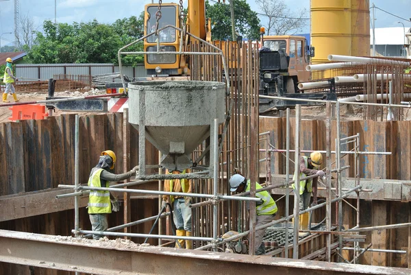 A group of construction workers pouring concrete into pile cap formwork — Stock Photo, Image