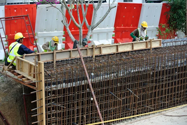 Trabalhadores da construção fabricam barra de reforço de parede de retenção no canteiro de obras . — Fotografia de Stock