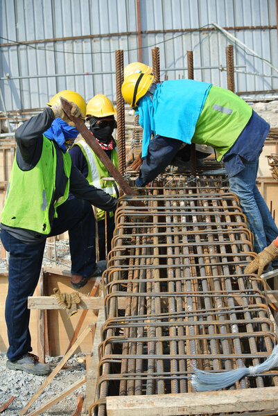 Construction workers fabricating ground beam reinforcement bar