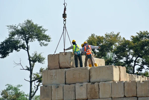 Trabajadores de la construcción apilando el bloque de prueba de carga de mantenimiento en el sitio de construcción —  Fotos de Stock