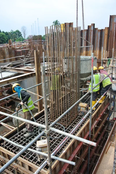 Stavební dělníci pomocí betonové vibrátor zkomprimovat konkrétní kejdy — Stock fotografie