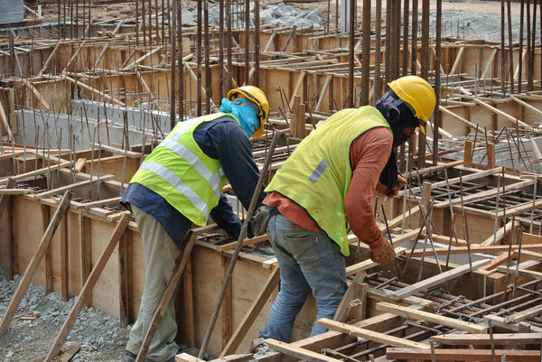 Group of construction workers fabricating ground beam formwork