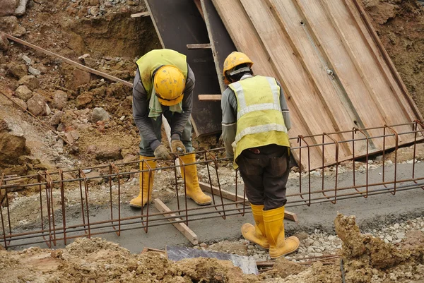 Grupo de trabajadores de la construcción que fabrican barra de refuerzo de acero de viga de tierra — Foto de Stock