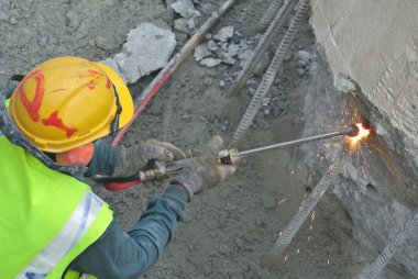İnşaat alanında metal kesme için kaynak makinesini kullanarak işçi.