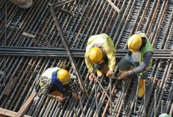 Grupo de trabajadores de la construcción que fabrican barras de refuerzo de acero — Foto de Stock
