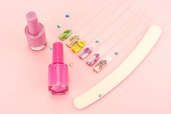 Nail designs on tips and manicure set on a pink background.