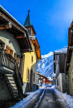 Street in a village in snowy mountain area. clipart