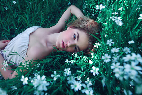 Girl lying in a clearing among white flowers White flowers. Chamomile.