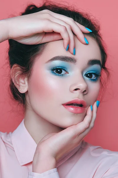 Menina com maquiagem azul, com unhas azuis em um fundo rosa . — Fotografia de Stock