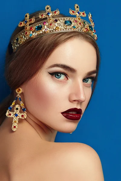 Girl with a golden crown and golden earrings. — Stock Photo, Image