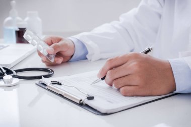 Doctor doing paperwork and using laptop in clinic. description into a server computer in hospital. Concept invented a cure, vaccine for coronavirus disease (COVID-19).