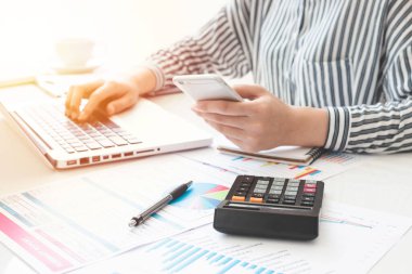 Business woman using calculator and writing make note with calculate. taxes and economic concepts. Savings, finances and economy concept through a laptop.