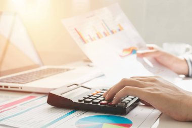 Business woman using calculator and writing make note with calculate. taxes and economic concepts. Savings, finances and economy concept through a laptop.