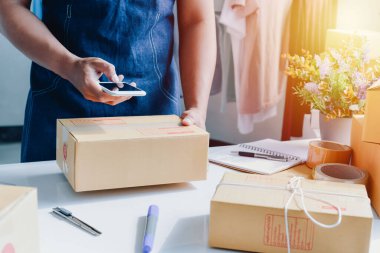 İnsan çevrimiçi dükkan sahibi küçük işletme sahibi girişimcinin posta kutusunu paketlediği ve teslimat paketini masaya koyduğu yakın plan görüntüsü. Girişimci serbest meslek kavramı.