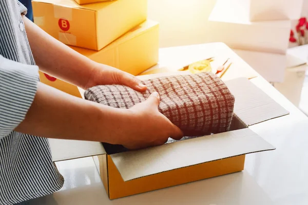 Closeup view of female online store small business owner seller entrepreneur packing package post shipping box preparing delivery parcel on table. entrepreneurial self employed business concept.