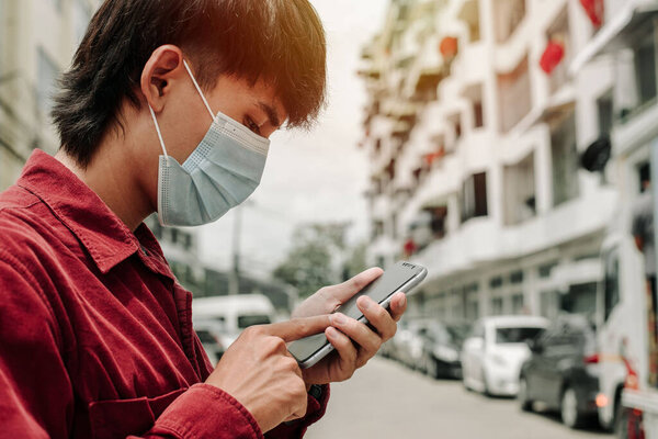 Man with medical face mask using the phone to search for news. Concept of coronavirus quarantine. MERS-Cov, Novel coronavirus (2019-nCoV)