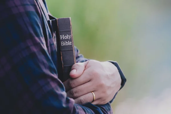 Man in hold and hugging holy bible on the bench. christian praying believe concept.