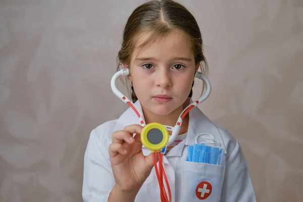 Dziecko bawiące się w lekarza trzymającego zabawkę Stetoskop na jasnym tle. — Zdjęcie stockowe